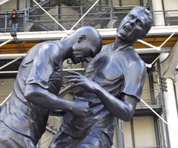 In a statue, French midfielder Zinedine Zidane uses his cranium to test the durability of Italian defender Marco Materazzi's sternum.