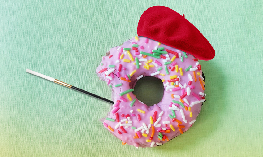 a pink krispy kreme donut with multi-colored sprinkles. it has a bite taken out of it. it is sporting a red beret and long cigarette holder